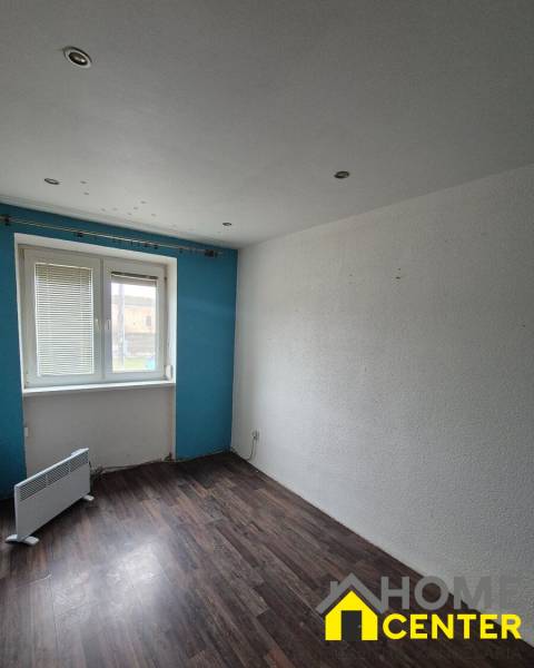 A room in a 3-room apartment with a wooden decor floor, blue wall, window with radiator.