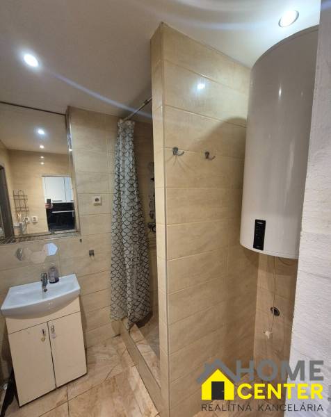 Bathroom in a 3-room apartment with beige tiles, a shower corner, and a sink.
