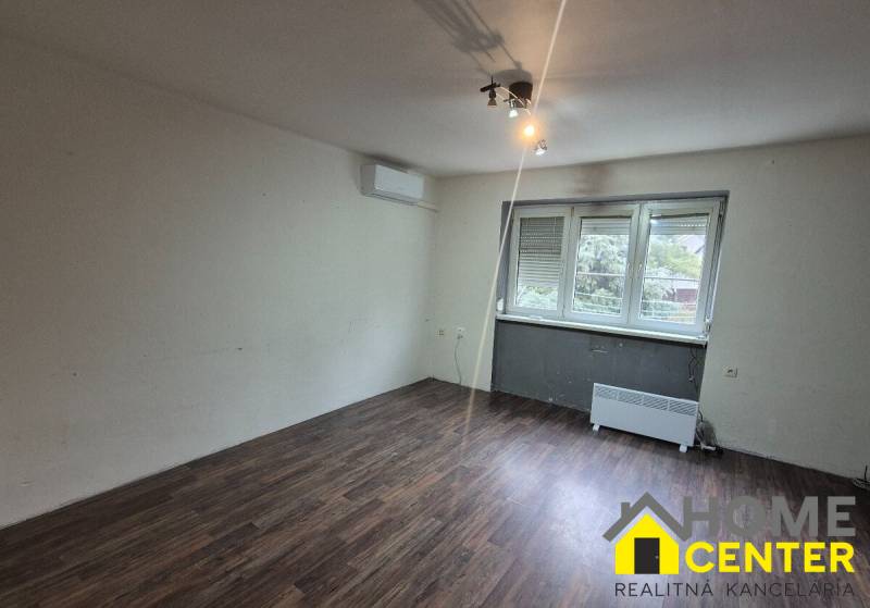 A room in a 3-room apartment with a wooden decor floor and a large window.