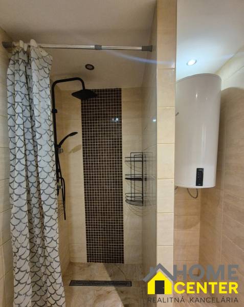 Bathroom in a 3-room apartment with an open shower, curtain, and electric boiler.