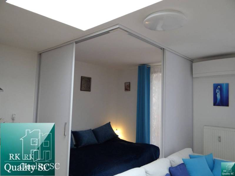 A one-room apartment with sliding doors, blue accessories, and decorative paintings on the wall.