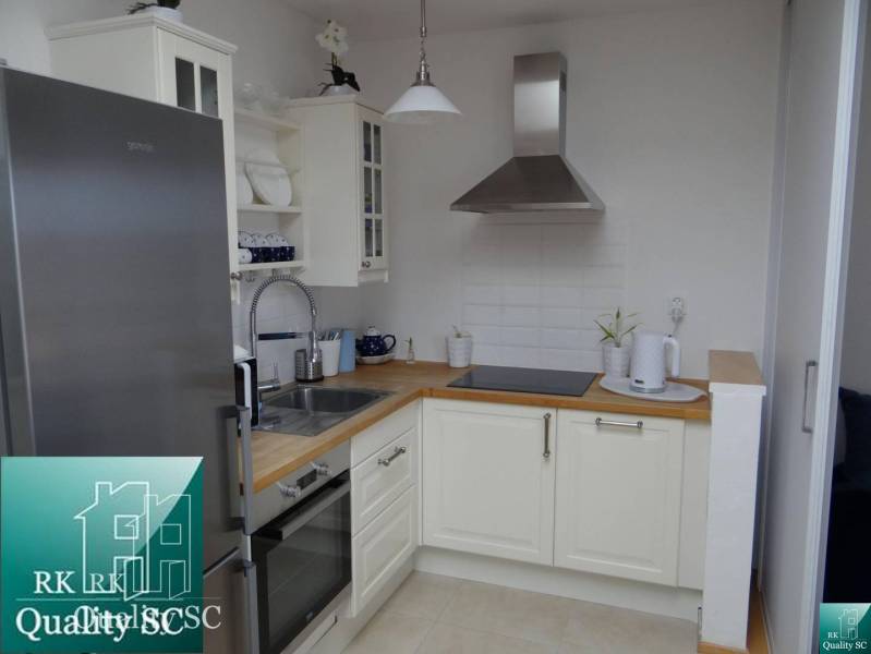 A kitchen in a studio apartment with white cabinets and stainless steel appliances.