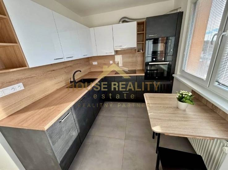 A kitchen in a 3-room apartment with light-colored furniture cabinets and a wooden decor floor.