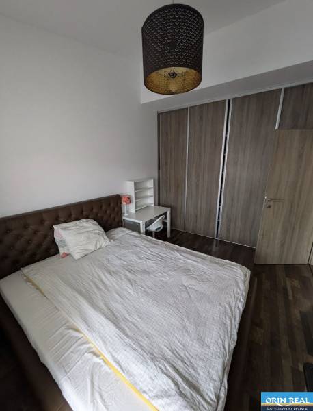 Bedroom with a bed, table, and wardrobe, 2-room apartment, floor with wood decor.