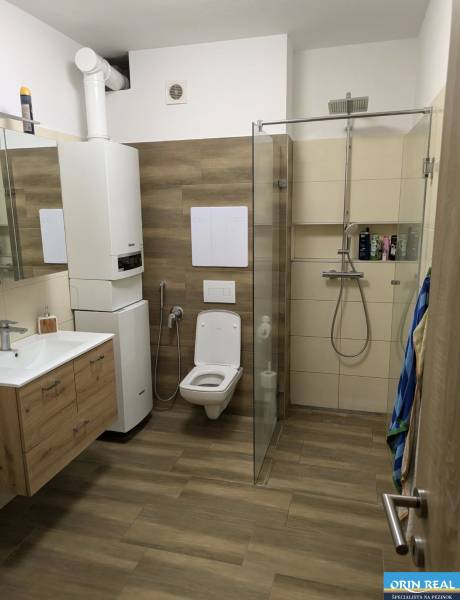Bathroom with wood-patterned flooring, shower, and toilet in a 2-room apartment.