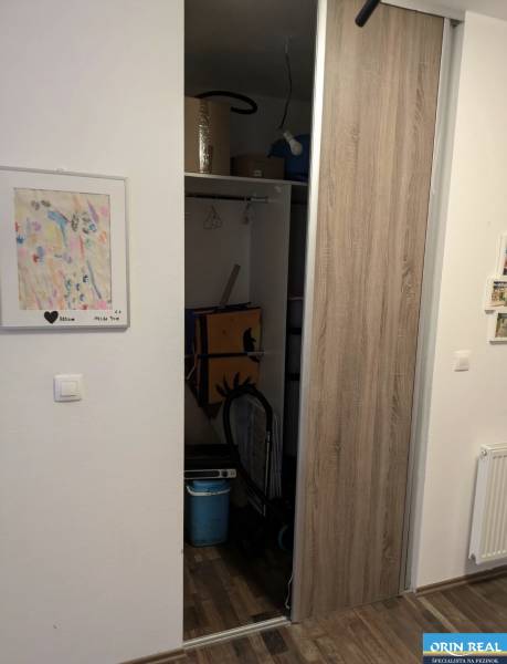 Storage space in a 2-room apartment with wooden decor and a children's drawing on the wall.