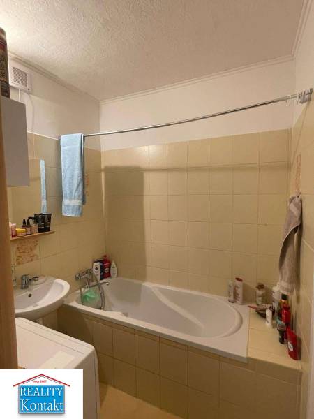 A bathroom in a 2-room apartment with a shower and light tiles.