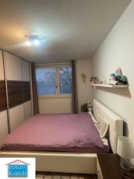 Bedroom in a two-room apartment with a double bed and a built-in wardrobe, floor with wood decor.