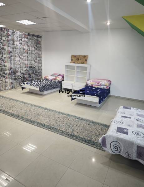 A room in a family house with three beds, a shelf, and light tiles.