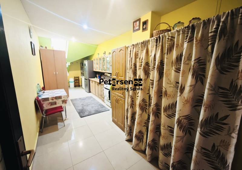 A kitchen in a family house with wooden decor, yellow walls, and patterned curtains.