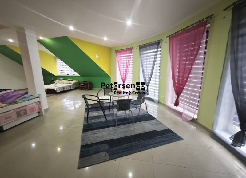 A bright living room with colorful walls, a seating area, and pull-out beds in a family house.