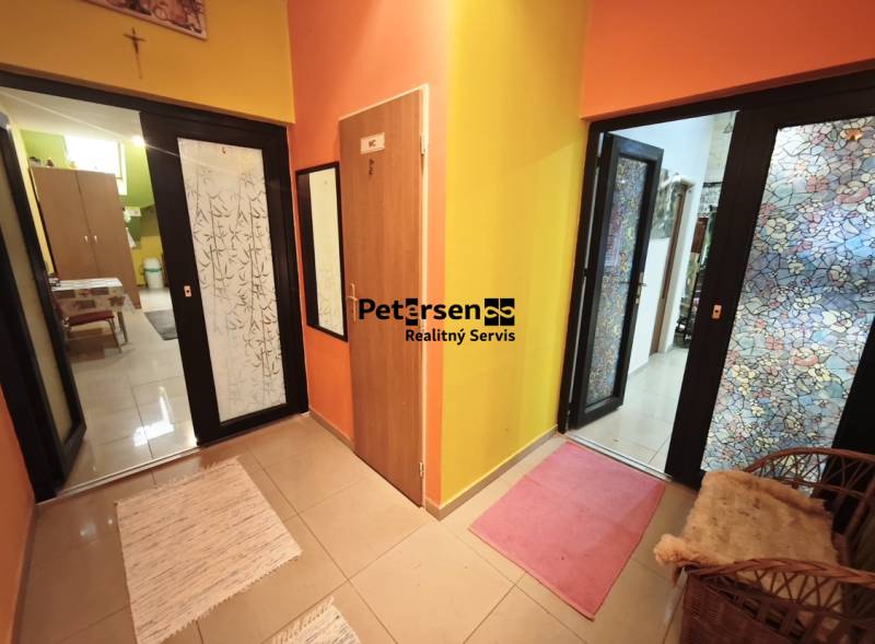 A hallway in a family house with colorful walls and rugs on the floor.