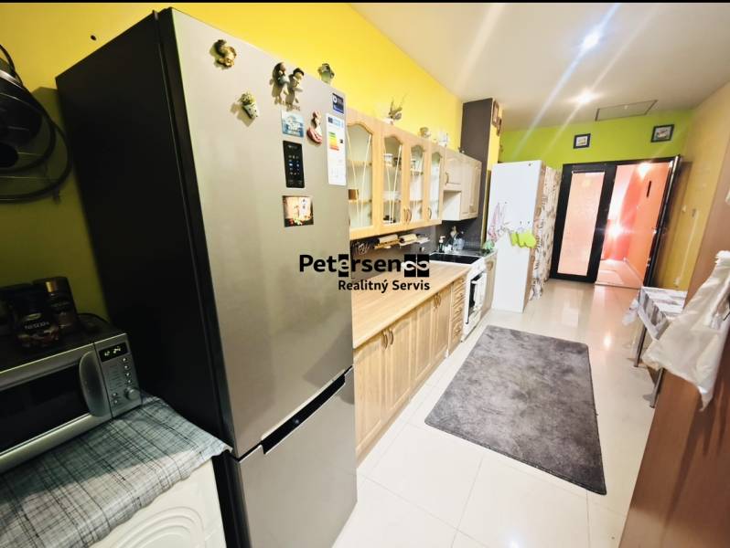 A kitchen in a family house with a stainless steel refrigerator and wooden decor cabinets.