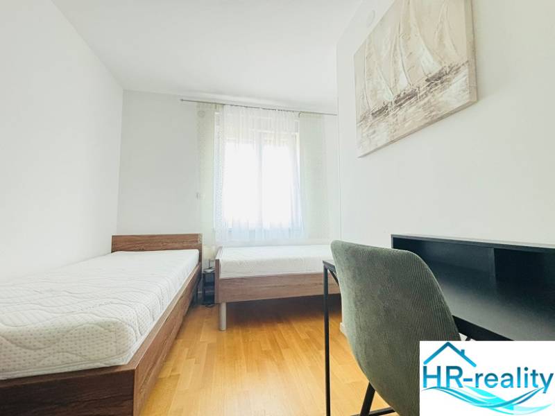 Bedroom in a holiday apartment with two beds and a wooden decor floor.