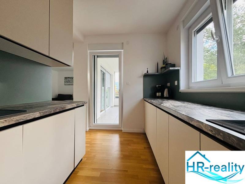 The kitchen of a holiday apartment with a wood-decor floor and a terrace.