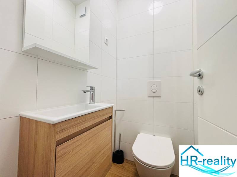 A bathroom in a vacation apartment with a sink, mirror, and floor with a wood decor.