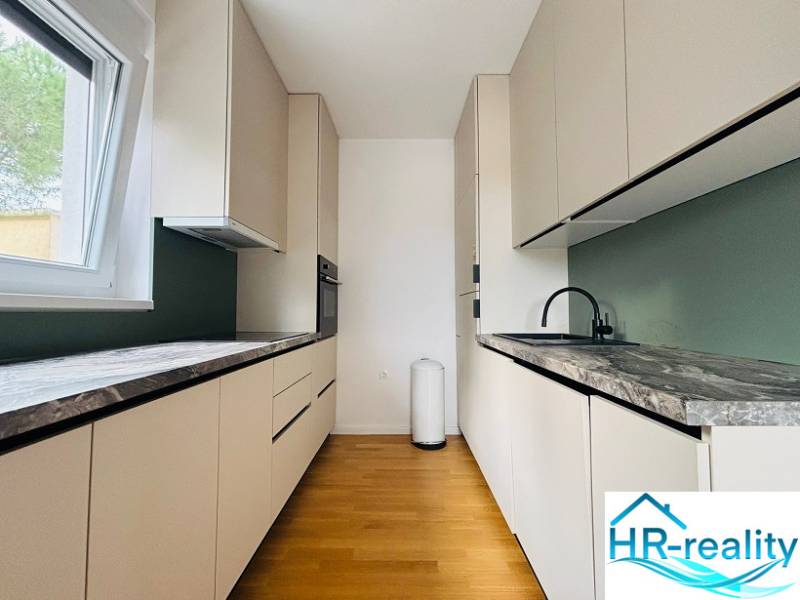 A kitchen in a holiday apartment with wood-patterned flooring and marble countertops.