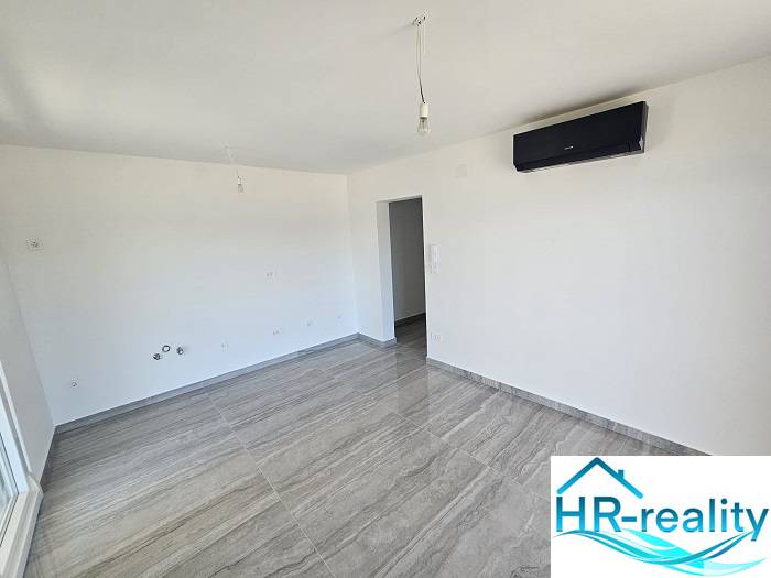 Room in a recreational apartment with air conditioning, light walls, and a floor with a wooden decor.