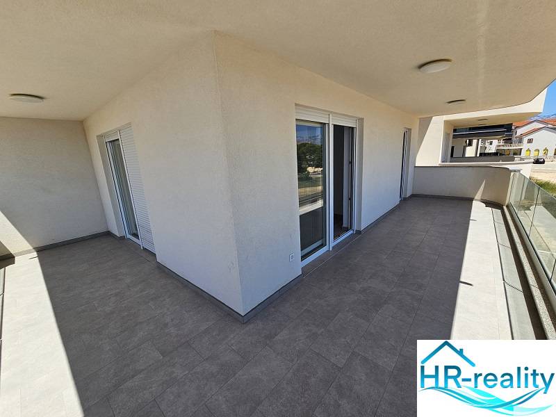 The large terrace at the holiday apartment in Povljana shines with a minimalist design and glass railings.