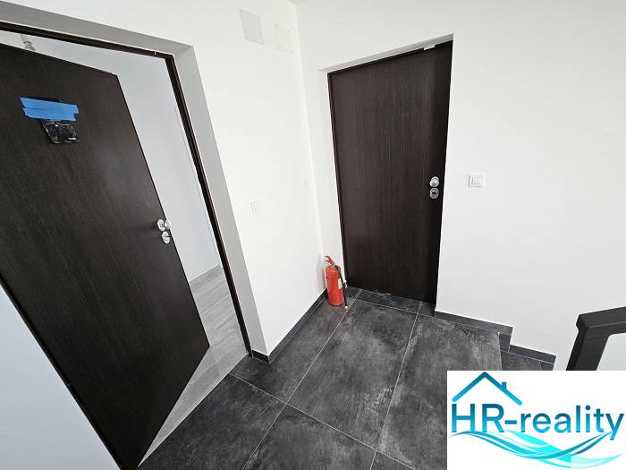 Interior of a holiday apartment with dark doors and flooring, fire extinguisher.