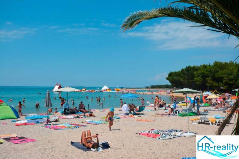 Sandy beach in Povljana near the holiday apartment with many visitors under umbrellas.