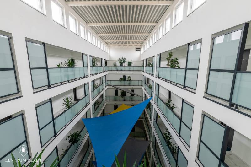 An interior atrium with transparent glass railings and colorful sails.