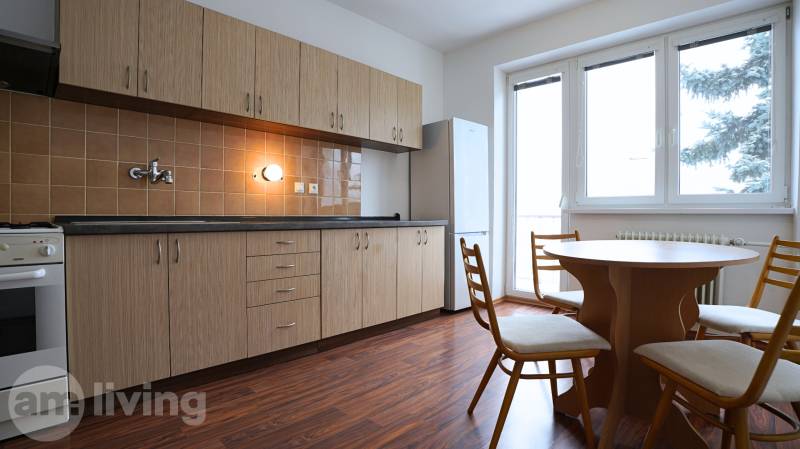 A kitchen in a 3-room apartment with a wooden decor floor and a dining table.