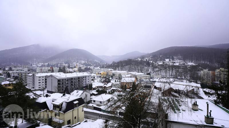 Snow-covered town of Trenčianske Teplice from Gogoľova Street with a view of the surrounding hills.
