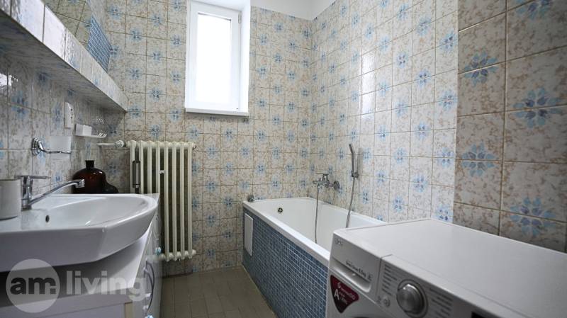 A bathroom with a bathtub and a washing machine in a 3-room apartment with retro tiles.