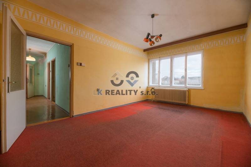 A room with a red carpet, yellow walls, and large windows in a family house.