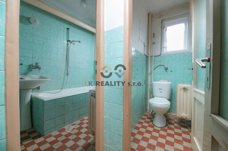 A bathroom in a family house with a bathtub and green tiles.