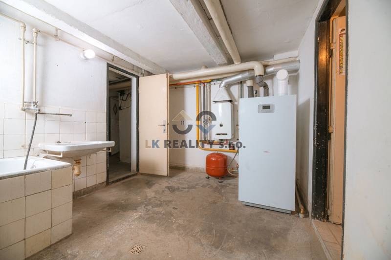 Basement space with a boiler in a family house, showing a sink and pipes.