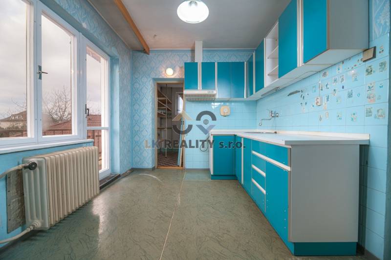 A kitchen in a family house with blue cabinets and a wood-patterned floor.