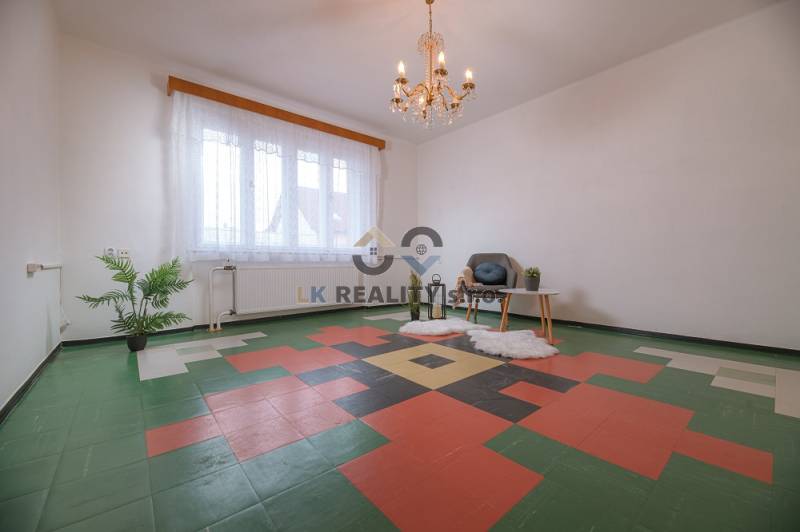 Interior of a family house with an ornamental floor, an armchair, a table, and a plant.