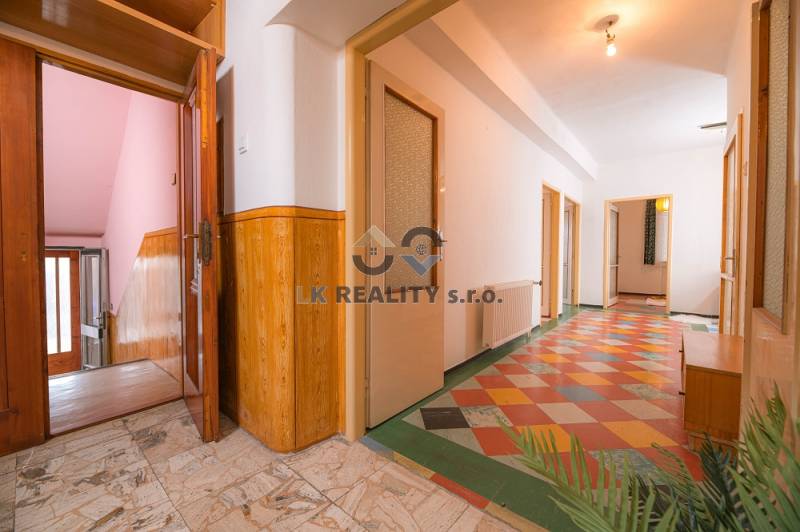 A hallway in a family house with a tiled floor and wooden accessories.