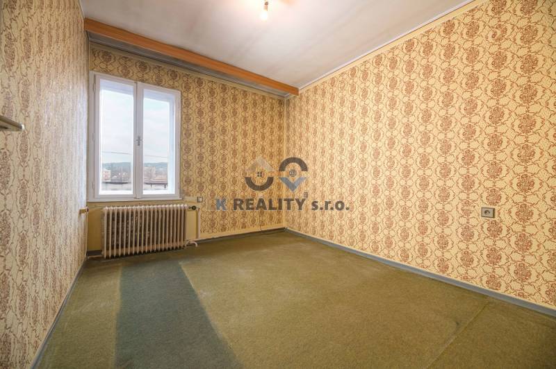 A room in a family house with patterned wallpaper and carpeted floor.