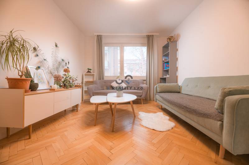 Living room in a 3-room apartment with a wooden decor floor, sofas, and plants.