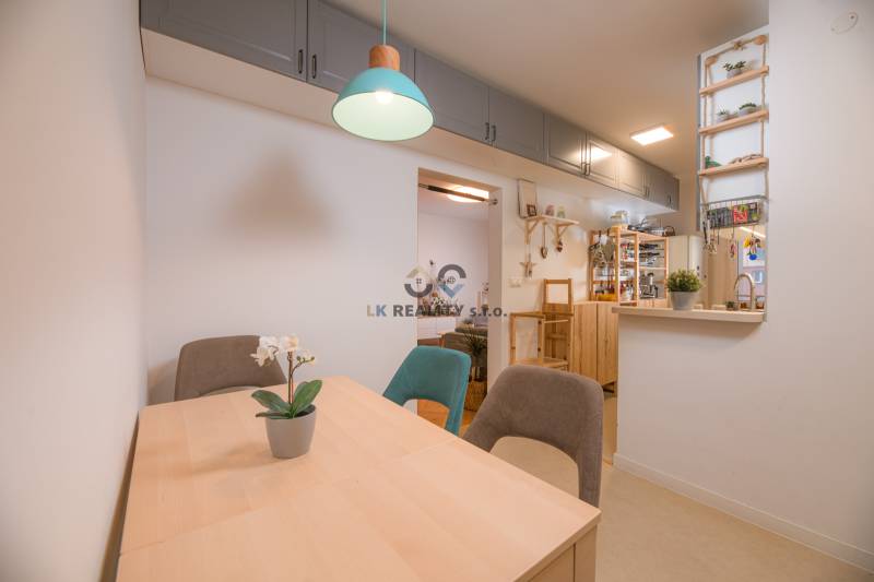 Dining table with chairs, light, shelves, and decorations in a 3-room apartment.