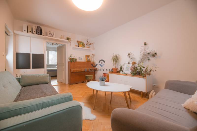 Living room in a 3-room apartment with a wooden decor floor, furniture, and plants.
