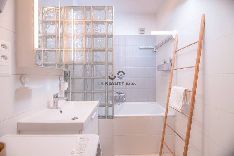 A bathroom with a bathtub, a sink, and a wooden ladder in a 3-room apartment.