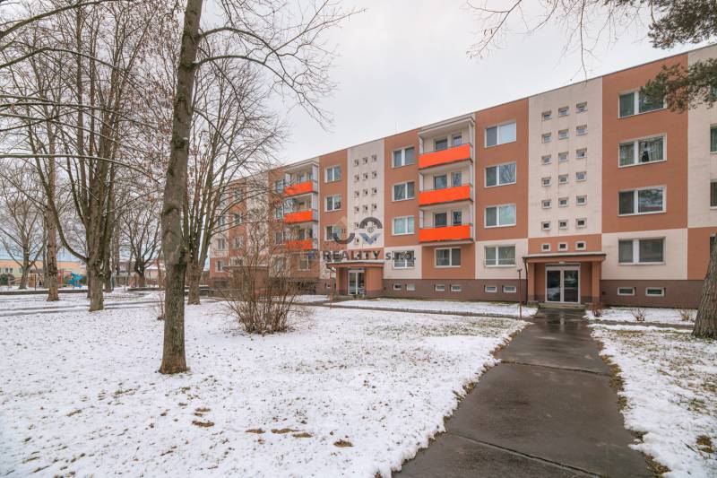 A four-story apartment building with a snow-covered lawn on Bezručova Street in Trenčín.