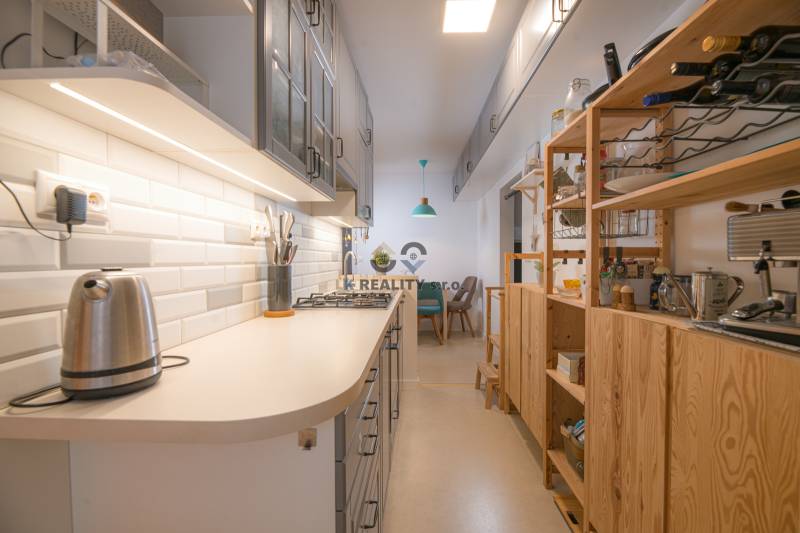 Cozy kitchen with wooden shelves and white tiles in a 3-room apartment.