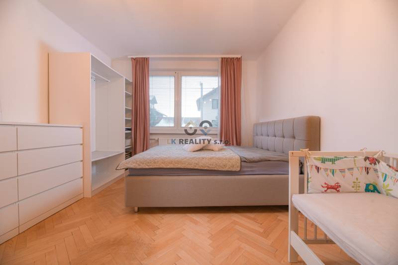 Bright bedroom with a built-in wardrobe and a crib in a 3-room apartment, floor with wood decor.