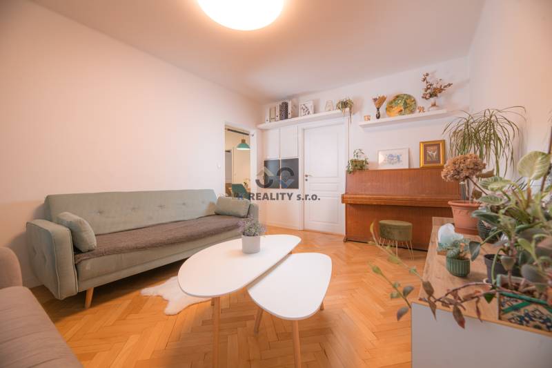 Living room of a three-room apartment with a wooden decor floor and a piano.