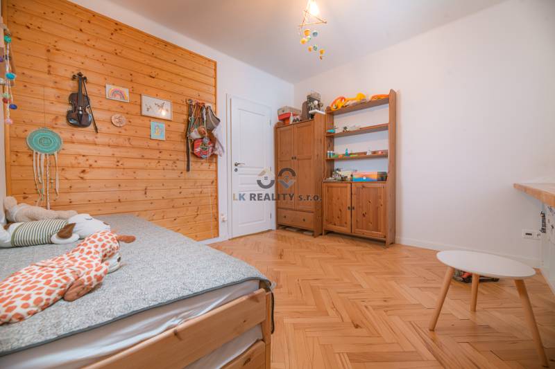 A room in a 3-room apartment with a wood-patterned floor and a decorative wooden wall.