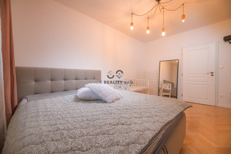 Bedroom in a 3-room apartment with a large bed and a wooden decor floor.