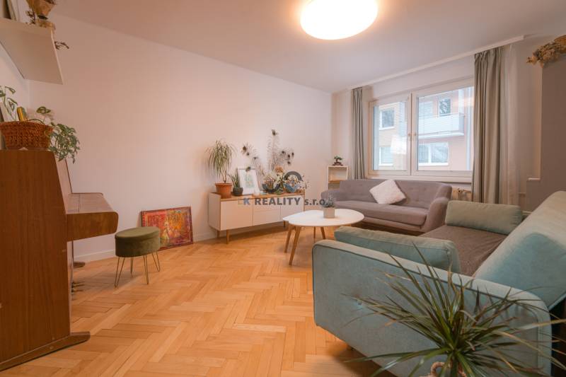 A bright living room with a piano, wooden decor flooring, and comfortable sofas.