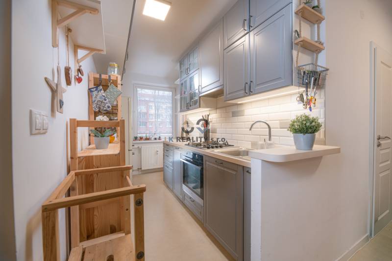 A kitchen in a 3-room apartment with a functional counter, wooden shelves, and light cabinets.