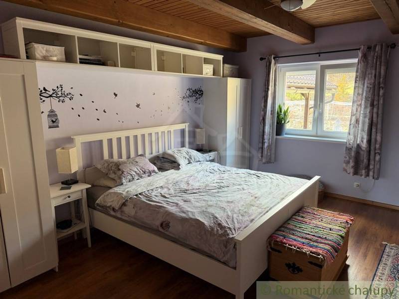 A bedroom with a wall featuring a tree design and a wooden-patterned floor in a family house.