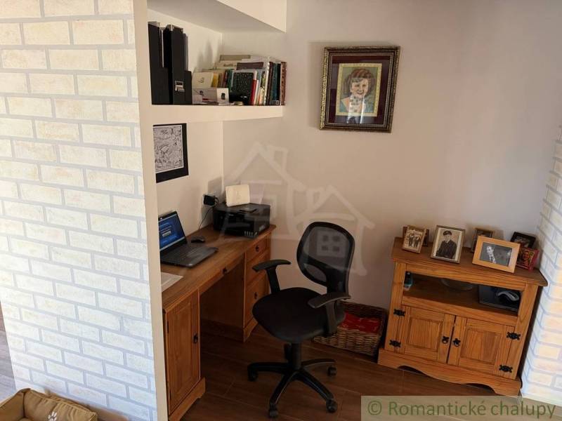 Home office with a desk, books, and photos on shelves in a family house.